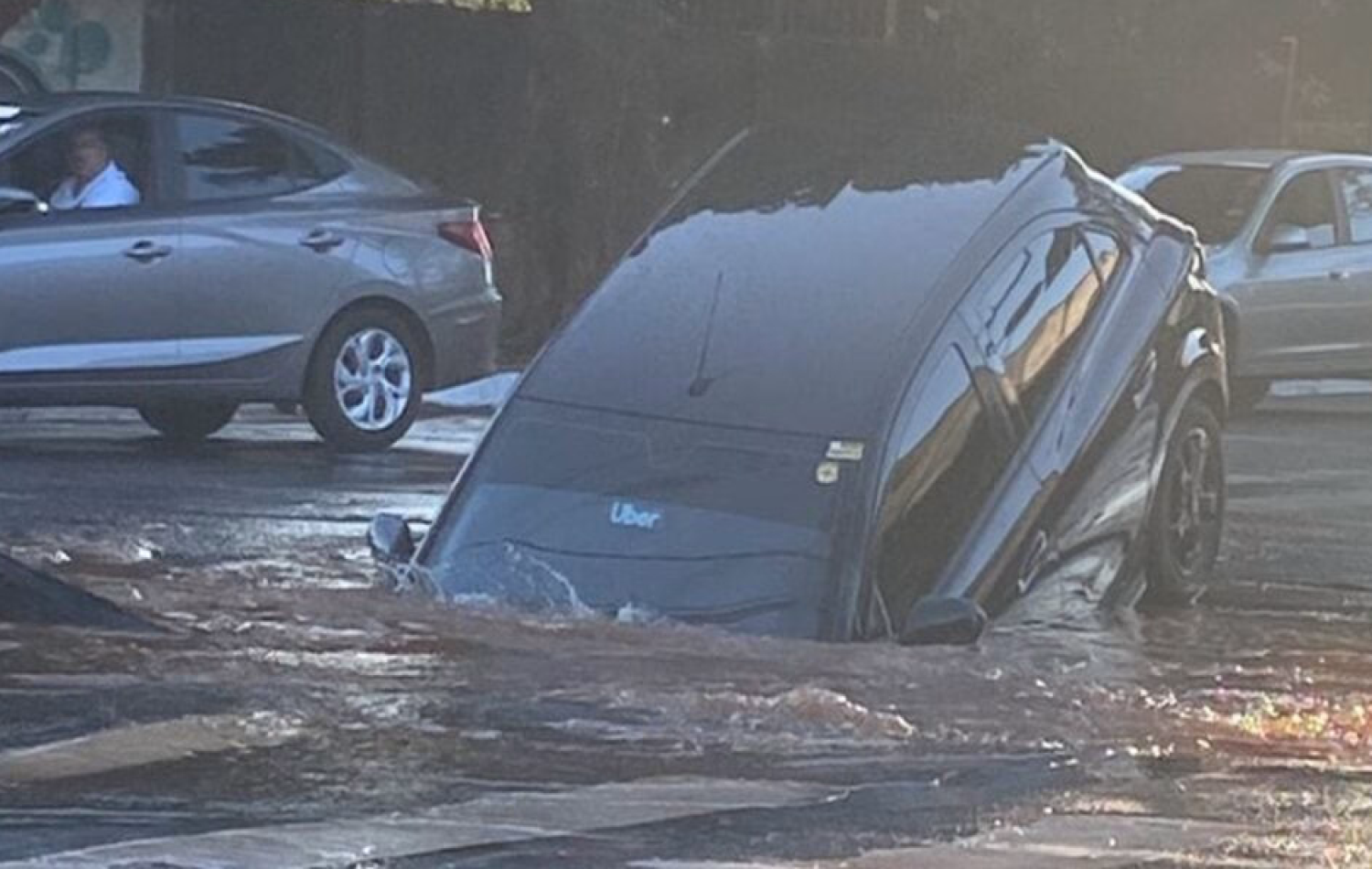 Carro cai em cratera após adutora de água se romper na Av. Independência, em Goiânia